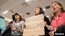 Seorang perempuan memegang tulisan berisikan protes larangan imigran yang ditetapkan oleh Presiden Donald Trump, di bandara internasional Dallas/Fort Worth di Dallas, Texas, 28 Januari 2017.
