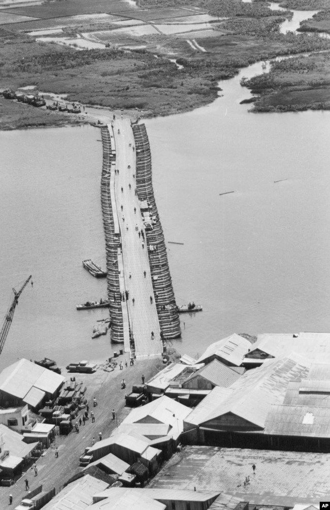 FILE - Military traffic is halted as U.S. Army engineers finish repairing a pontoon bridge damaged by a Viet Cong underwater mine, August 1968. Linking Saigon with the Mekong Delta, the bridge over the Oriental River replaced the permanent bridge, blown up by the enemy.