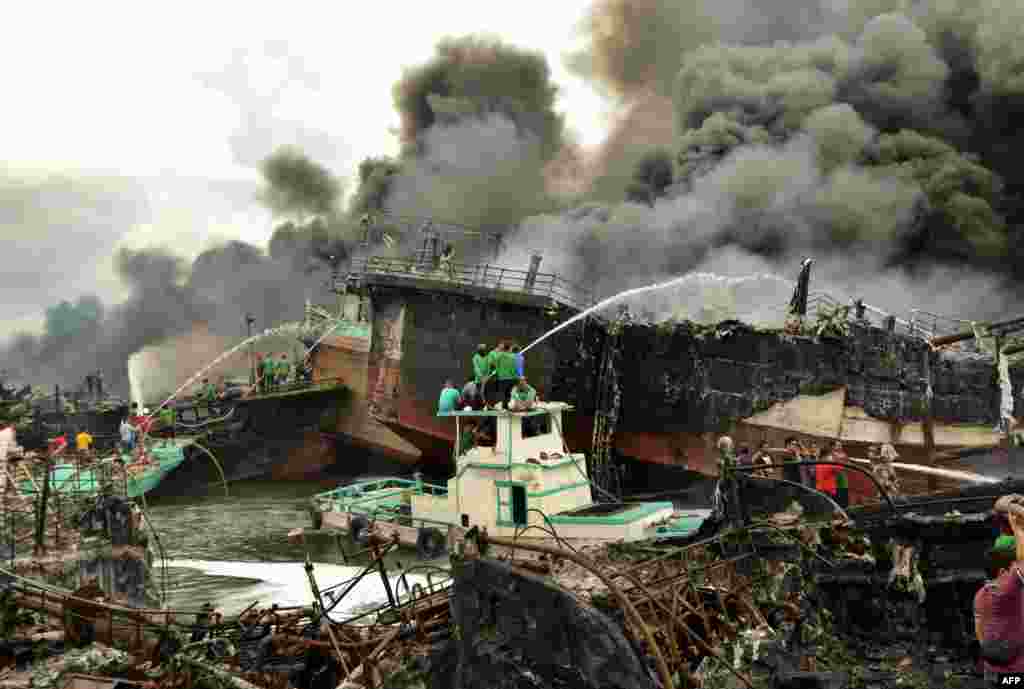 Indonesia firefighters try to extinguish a fire on fishing boats at Benoa harbour in Denpasar, on Indonesia&#39;s resort island of Bali.