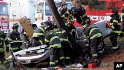 Seattle Fire Dept. firefighters swarm over a car as they work to cut passengers from the wreckage after the vehicle smashed into a tree just short of a pedestrian path at Green Lake park in Seattle, Thursday, Dec. 21, 2006. Three young men were critically injured in the crash, which closed northbound Aurora Avenue. (AP Photo/Elaine Thompson)