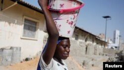 Seorang anak perempuan membawa ember berisi air bersih di Pikine, pinggiran Kota Dakar, Senegal, 9 Maret 2020. (Foto: Reuters)