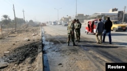 Iraqi security forces stand at the site of car bomb attack in the predominately Shi'ite Muslim neighbourhood of al-Obaidi, Iraq, Jan. 5, 2017.