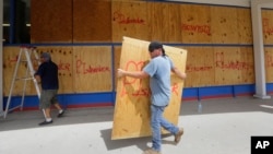 James Redford carries a sheet of plywood as he helps board up windows in preparation for Hurricane Harvey in Corpus Christi, Texas, Aug. 24, 2017.