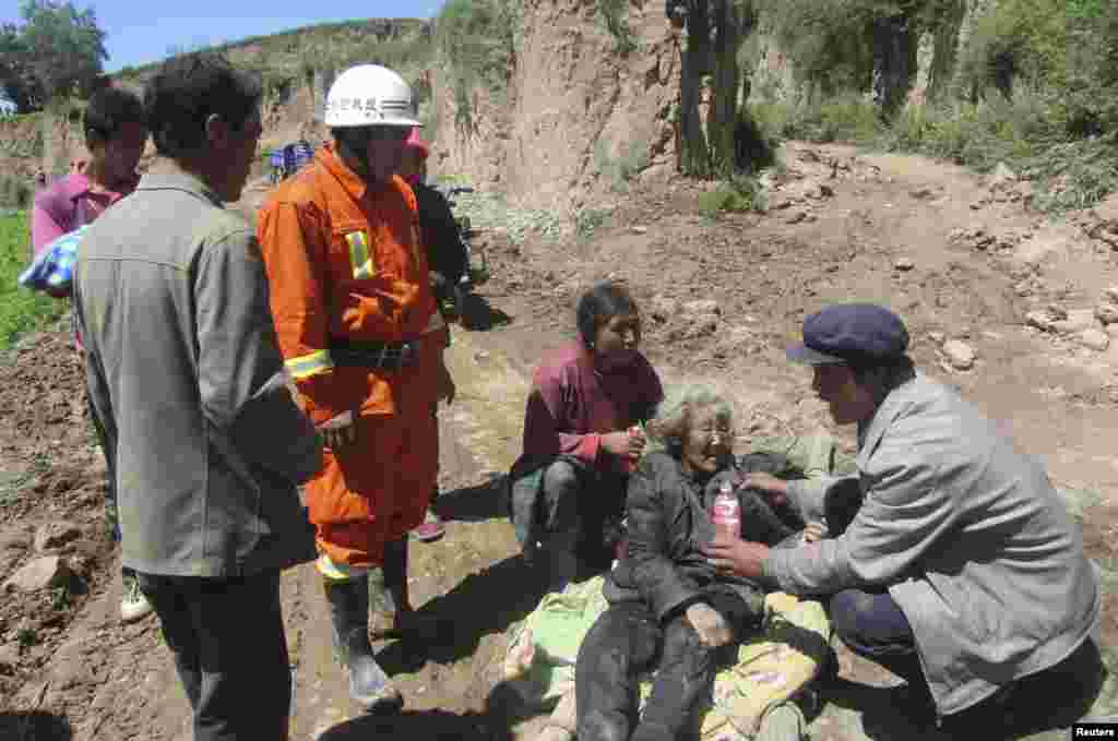 A man gives water to an injured woman on a stretcher after an earthquake hit Minxian county, Dingxi, Gansu province, China, July 22, 2013. 