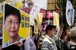 FILE - Protesters raise placards and banner during a rally against Hong Kong's former Chief Secretary Carrie Lam in Hong Kong, Feb. 5, 2017.