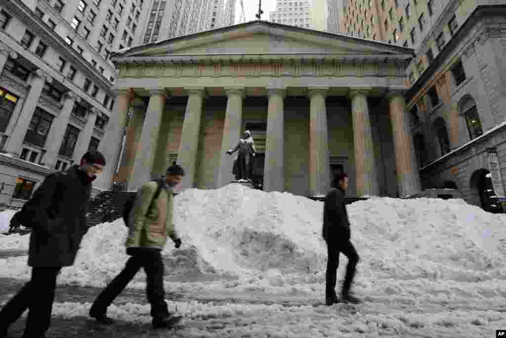 Morning commuters pass a pile of snow on Wall Street in New York&#39;s Financial District, Jan. 25, 2016.