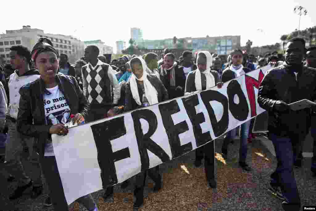Para imigran Afrika memegang spanduk berisi tulisan yang menuntut kebebasan kawan-kawan mereka yang dipenjara atas tuduhan pencarian pekerjaan yang ilegal oleh Israel.