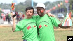 FILE: An unidentfied Chinese national and a Zimbabwean man hug while welcoming Chinese President Xi Jinping upon his arrival in Harare, Zimbabwe, Tuesday, Dec. 1. 2015. Jinping is in Zimbabwe for a two day State visit. (AP)