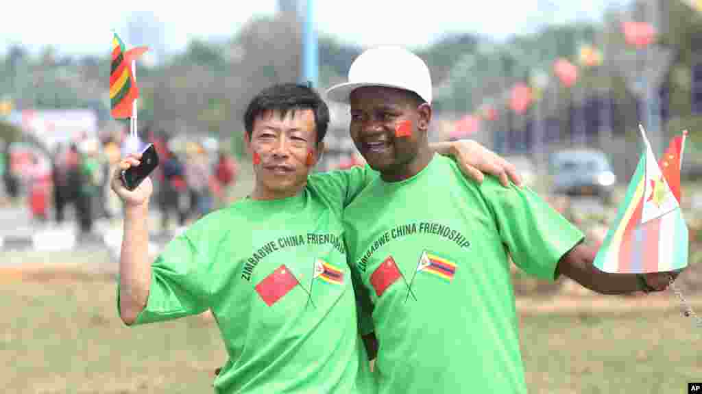 An unidentfied Chinese national and a Zimbabwean man hug while welcoming Chinese President Xi Jinping upon his arrival in Harare, Zimbabwe, Tuesday, Dec. 1. 2015. Jinping is in Zimbabwe for a two day State visit during which he is set to sign some bilateral agreements aimed at strengthening relationships between the two countries. 