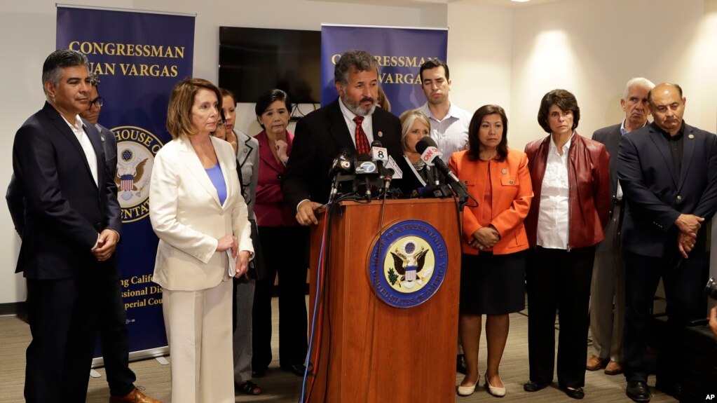 La líder de la minoría de la Cámara de Representantes Nancy Pelosi, demócrata de California (segunda desde la izquierda), observa mientras el representante federal Juan Vargas, demócrata de California, habla en el podio frente a miembros del Caucus hispano del Congreso durante una visita a la frontera, el lunes, 18 de junio de 2018, en San Diego. Los miembros del Congreso hablaron sobre su visita a las instalaciones de detención de inmigración del área. (AP Photo / Gregory Bull).