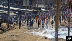 Pendukung kelompok oposisi melemparkan batu kemudian lari ketika polisi menembakkan gas air mata dalam bentrokan di Kawangware, Nairobi, Kenya, 28 Oktober 2017. 