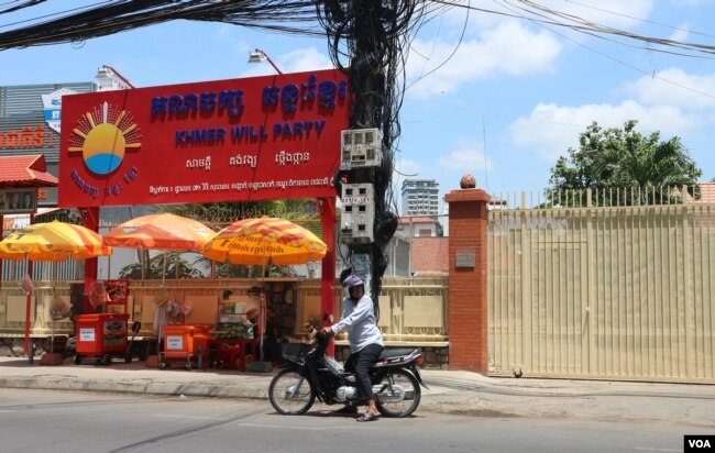 បុរសម្នាក់ឈប់ម៉ូតូនៅខាងមុខទីស្នាក់ការគណបក្សឆន្ទៈខ្មែរក្នុងខណ្ឌចំការមន ដែលកំពុងបិទទ្វារ នាថ្ងៃបើកយុទ្ធនាការថ្ងៃទី១នៃការឃោសនារកសំឡេងគាំទ្រសម្រាប់ការបោះឆ្នោតជ្រើសរើសក្រុមប្រឹក្សា អាណត្តិទី៣ នៅថ្ងៃទី១៧ ខែឧសភា ឆ្នាំ២០១៩។ (កាន់ វិច្ឆិកា/VOA Khmer)