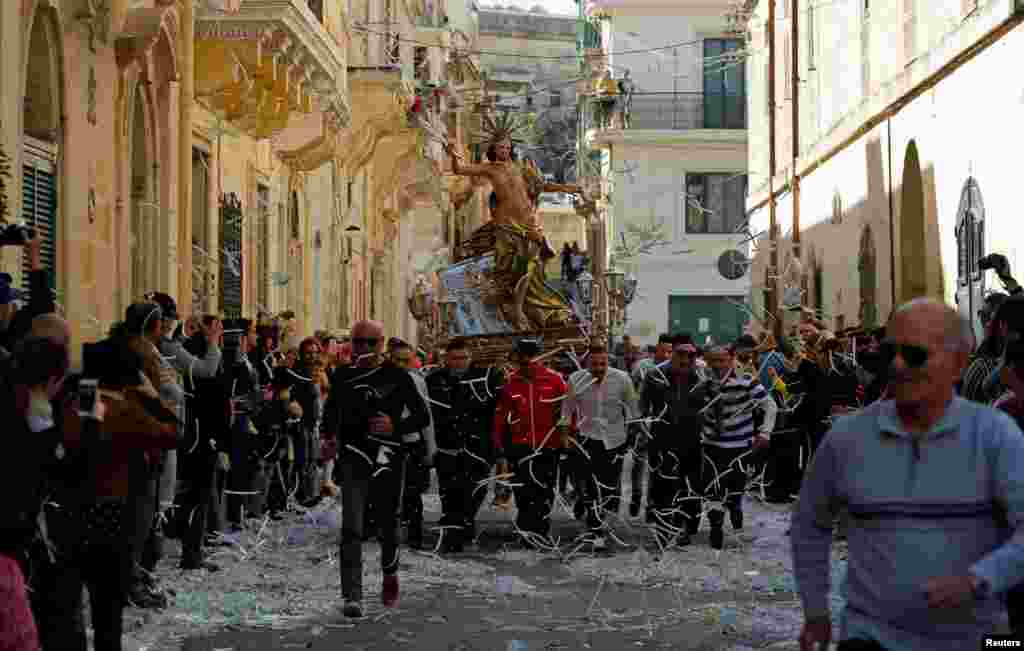 Worshipers carrying a statue of the Risen Christ run during an Easter Sunday procession in Cospicua, Malta.