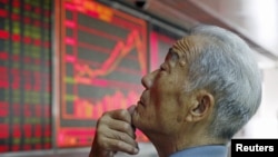 File - An investor watches an electronic board showing stock information at a brokerage office in Beijing, China, July 2015.