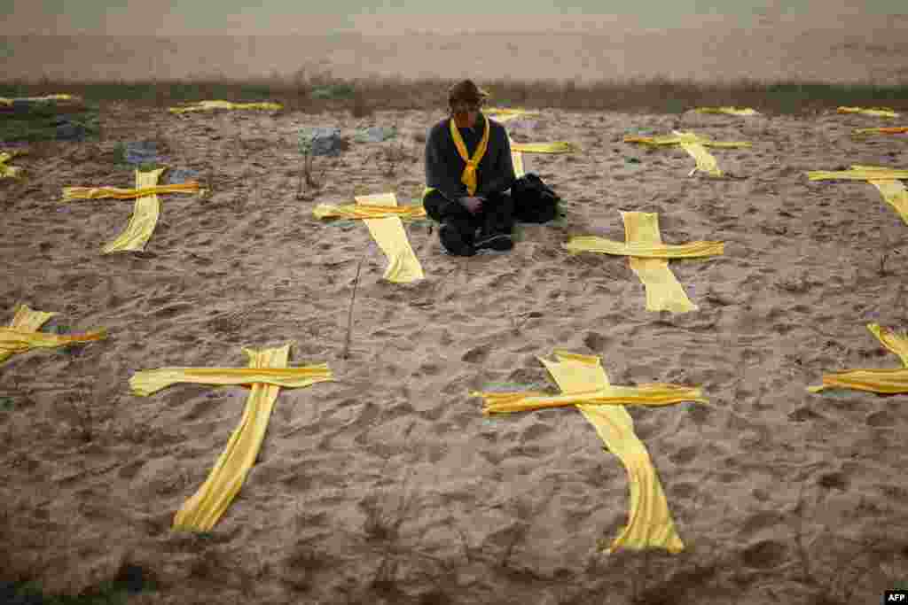 A woman sits on the beach among yellow crosses during a protest called by local Republic Defence Committees (CDR), in support for jailed separatist leaders, at Mataro's beach, near Barcelona, Spain.