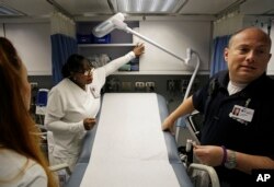 Nurses Tessa Sheffield, from left, Evelyn Fields and Greg Miller look over a mobile emergency room set up outside Grady Memorial Hospital to help handle the ever-growing number of flu cases in Atlanta, Jan. 29, 2018.