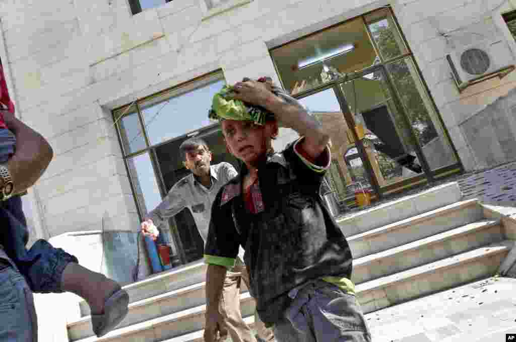 Wounded Syrians evacuate a field hospital after a second air strike in Azaz on the outskirts of Aleppo, August 15, 2012.