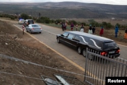 A convoy of police and funeral vehicles approaches the home of Mandla Mandela, a grandson of ailing former S. African President Nelson Mandela, following a court hearing clearing the way to remove the remains of the former leader's children from his prope