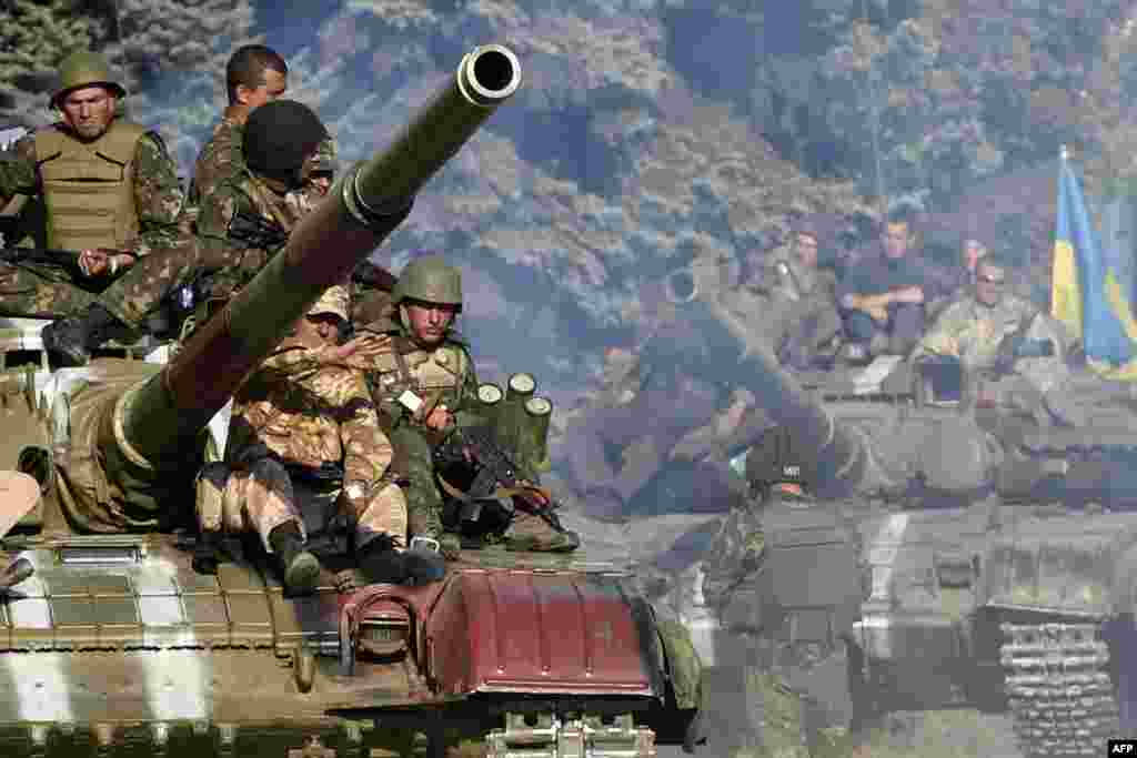 Ukrainian army soldiers ride a tank on a road near where pro-Russian separatists fired heavy artillery, on the outskirts of the key southeastern port city of Mariupol, Sept. 5, 2014.