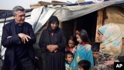 Filippo Grandi, à gauche, le Haut-commissaire de l'ONU pour les réfugiés, parle avec une famille syrienne au camp de Saadnayel, Liban, 22 janvier 2016.