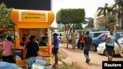 In this photo taken Sept. 29, 2016, Ugandans use a mobile money point in Kampala. Mobile money has become a way of life for many Africans.