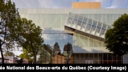 The southwest side of the Pierre Lassonde Pavilion reflects the park surrounding the museum. Inside the pavilion, one can see a concrete wall that is integrated with the church next door.