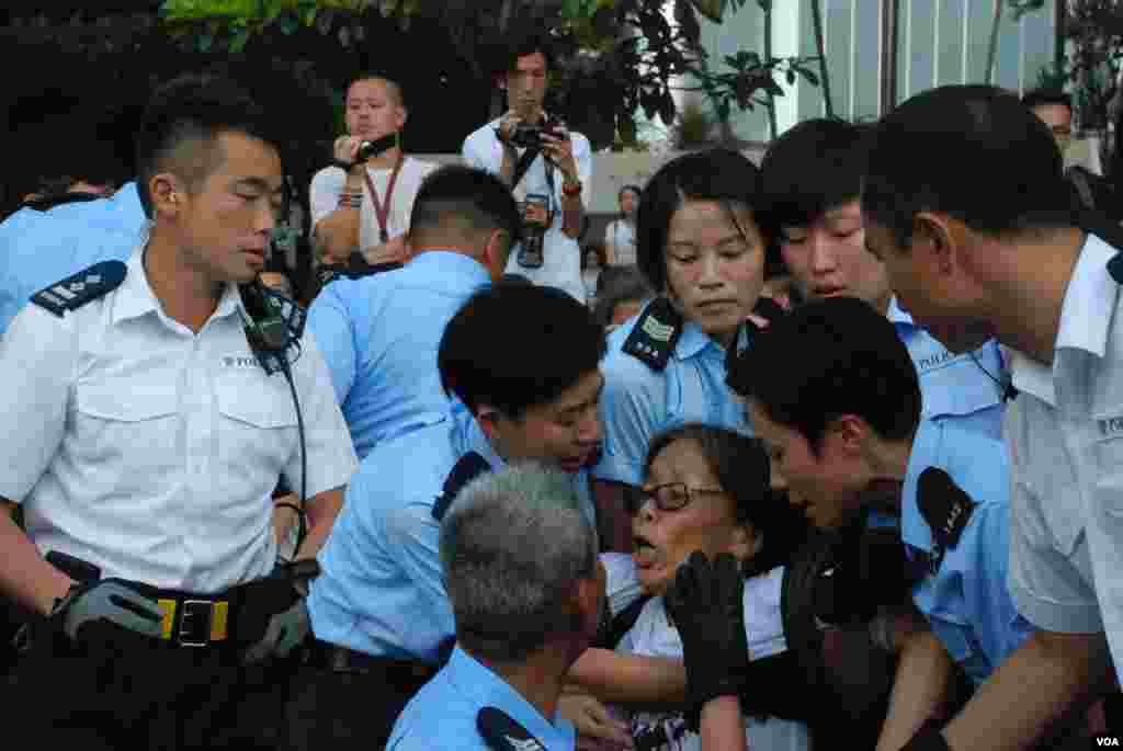 數名警員合成將在現場指揮靜坐人士的香港理工大學退休副教授何芝君抬離遮打道