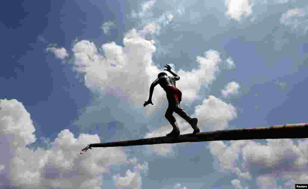 A boy climbs up a greasy pole in a climbing competition at a part of Sinhala, the Hindu and Tamil New Year celebrations, in Bandaragama, Sri Lanka, April 21, 2018.