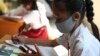 Seorang siswi mengenakan masker untuk mencegah penularan virus corona sedang belajar daring dengan memanfaatkan akses wifi gratis di kantor Kelurahan Jatirahayu, Bekasi, 27 Juli 2020. (Foto: AP) 