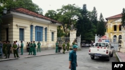 FILE - Policemen and security staff stand outside the main entrance gate of Ho Chi Minh City's People's Court where three bloggers stand trial for 'anti-state propaganda'.