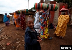FILE - A boy smiles at the camera as Nubian women take part in a procession to newly-wedded bride Zubeda Mohamed Ahmed's home, bearing gifts seven days after her wedding in accordance with Nubian culture, at Makina village in Nairobi's Kibera slum.
