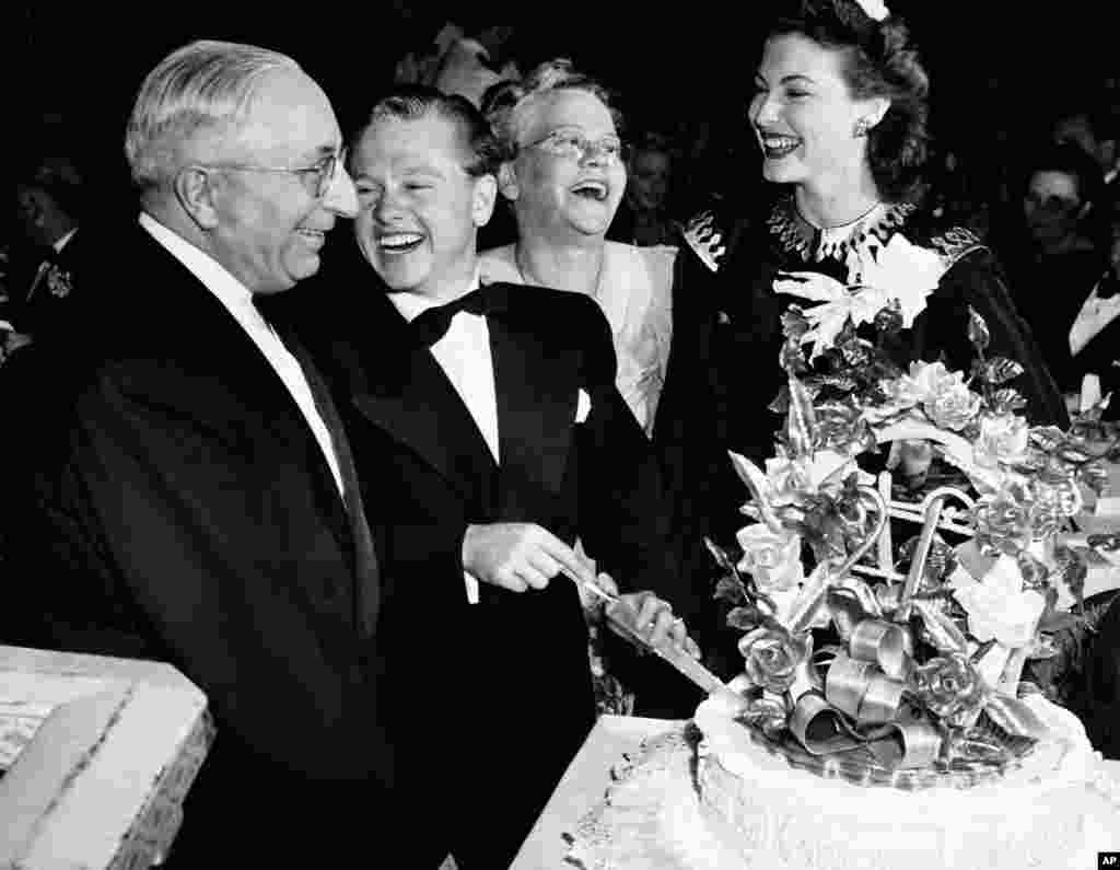 Film actor Mickey Rooney celebrates his 21st birthday at a party in a Hollywood night club. Here he slices his birthday cake with (left to right) Louis B. Mayer, studio head; Mrs. Nell Pankey, his mother, and Miss Ava Gardner,&nbsp;Hollywood, California, Sept. 23, 1941.