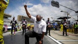 A NASCAR official kneels during the national anthem before a NASCAR Cup Series auto race at Atlanta Motor Speedway, Sunday, June 7, 2020, in Hampton, Ga. (AP Photo/Brynn Anderson)