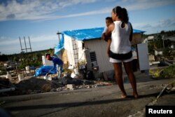 Samuel Vasquez rebuilds his house, which was partially destroyed by Hurricane Maria, while his wife Ysamar Figueroa looks on, whilst carrying their son Saniel, Dec 11, 2017.