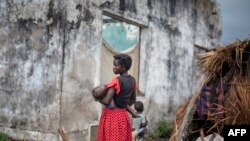 FILE - A woman holds her child at a makeshift camp for internally displaced persons (IDPs) among old abandoned buildings in Kalemie, Tanganyika province, Democratic Republic of the Congo, Sept. 18, 2017.