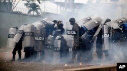 Police stand amid tear gas as they clash with supporters of opposition presidential candidate Salvador Nasralla near the institute where election ballots are stored in Tegucigalpa, Honduras, Nov. 30, 2017. Protests are growing as incumbent President Juan Orlando Hernandez emerged with a growing lead for re-election following a reported computer glitch that shut down vote counting for several hours.