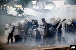 Police stand amid tear gas as they clash with supporters of opposition presidential candidate Salvador Nasralla near the institute where election ballots are stored in Tegucigalpa, Honduras, Nov. 30, 2017. Protests are growing as incumbent President Juan