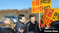 5일 경기도 남양주시 지금동에서 열린 합동참모본부 땅굴 탐사 결과 현장설명회에서 땅굴알림연대 및 땅굴안보국민연합 회원들이 피켓을 들고 국방부 관계자들을 둘러싸자 김민석 국방부 대변인(왼쪽 두번째)이 저지하고 있다. 한국 군은 조사 결과 이들이 주장한 곳은 땅굴이 아니라고 결론을 내렸다.