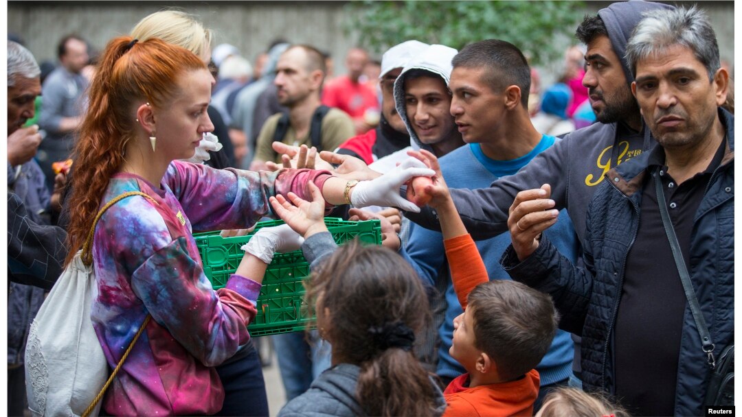 A helper distributes fruit to migrants in front of the State Office for Health and Social Affairs (LaGeSo), in Berlin, Germany, Sept. 3, 2015.