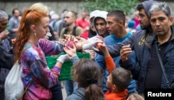 A helper distributes fruit to migrants in front of the State Office for Health and Social Affairs (LaGeSo), in Berlin, Germany, Sept. 3, 2015.