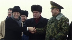 Secretary of Defense William Perry, left, shakes hands with Ukraine Defense Minister Valery Shmarov, center, and Russian Defense Minister Pavel Grachev as they stand over the crater which formerly housed a missile silo at a military base. (Yefrem Lukatsky/AP)