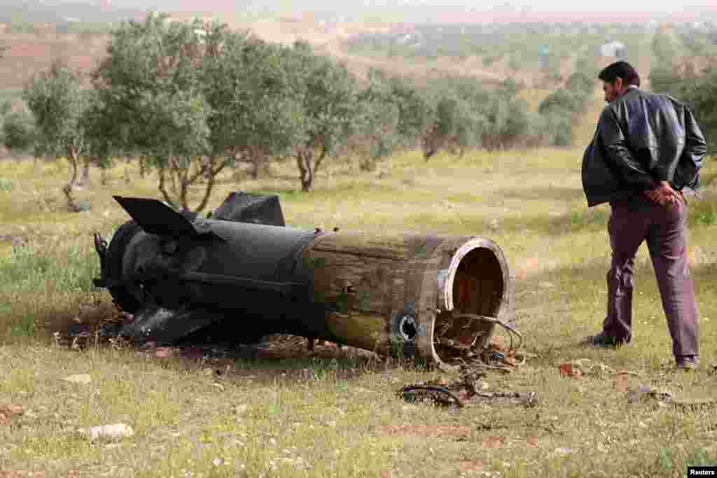 A man inspects a piece of a rocket that landed south of Daraa Al-Balad, Syria.