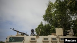 A Ugandan police officer serving with the African Union Mission in Somalia's first Formed Police Unit stands at the top of an armored personnel carrier at a police station in the capital Mogadishu, August 7, 2012.