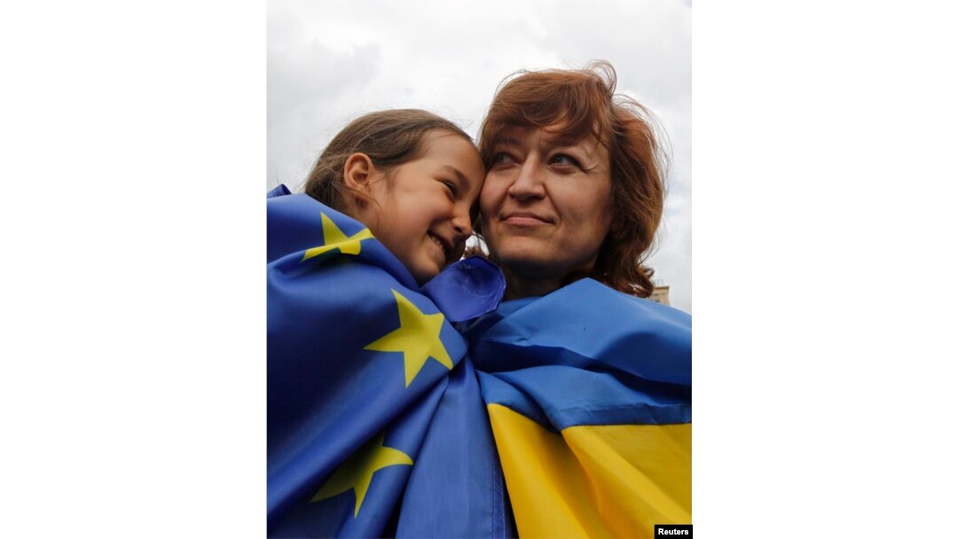 A girl and woman, respective draped in European Union and Ukrainian national flags, celebrate in Independence Square in Kyiv June 27, 2014.