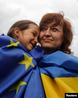 A girl and woman, respective draped in European Union and Ukrainian national flags, celebrate in Independence Square in Kyiv June 27, 2014.