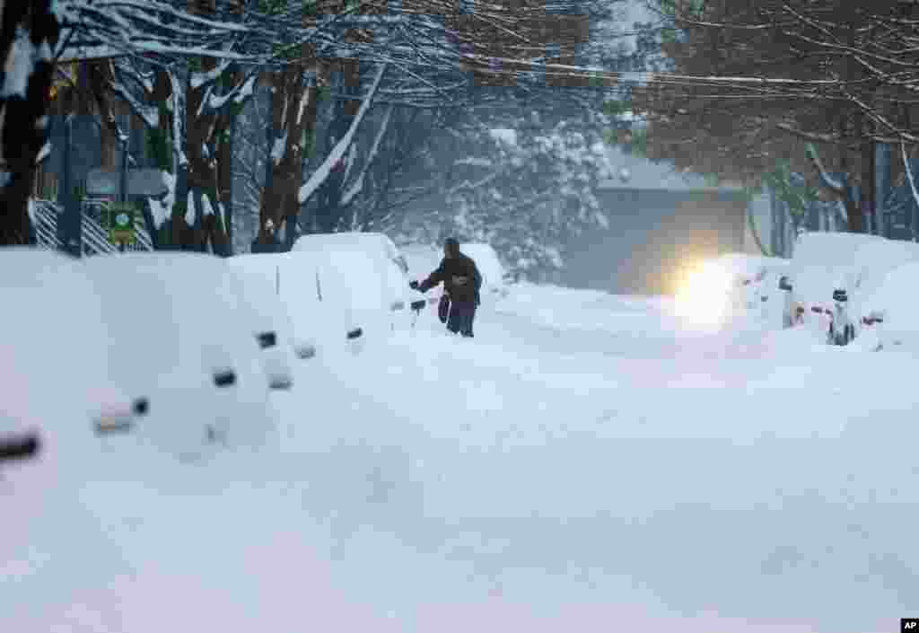 A motorist opens a car door before digging out in Albany, New York. Schools are closed across a swath of eastern New York from the mid-Hudson Valley to the Albany area as the region starts to dig out from 12 to 20 inches of snow dumped by the latest winter storm.