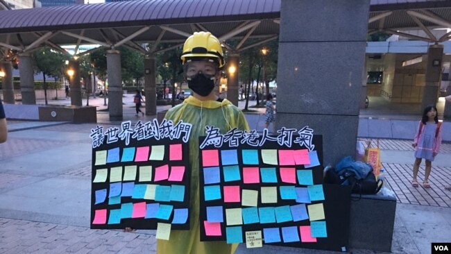 一位自称参加了香港“反送中运动”所有大游行的香港女学生在台北车站广场举起“连侬板”。（2019年7月27日，美国之音林枫拍摄）