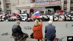 Pro-Russian activists with Russian flag sitting at a barricade at the regional administration building in Donetsk, Ukraine, April 23, 2014. 