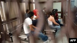 Part of a group of fourteen suspected members of a ring of human traffickers are kept in a holding cell in court in Guatemala City, August 9, 2012.