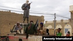 Fighters from Islamist group Ansar Dine stand guard as they prepare to publicly lash a member of the Islamic Police found guilty of adultery, in Timbuktu, Mali, Aug 31, 2012.